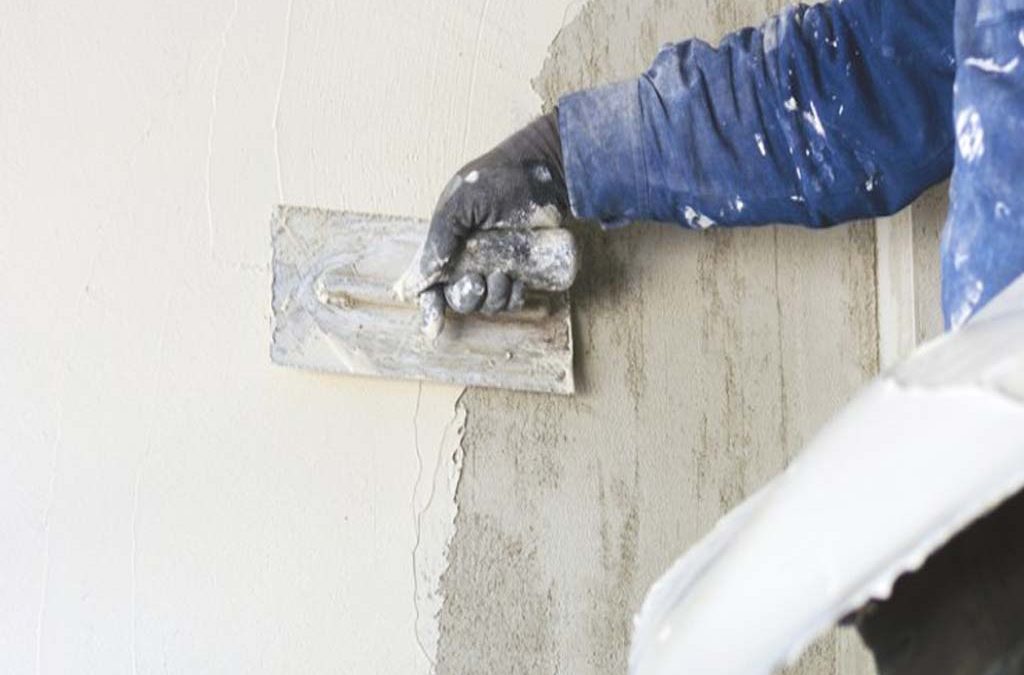 Worker applying wall putty on interior wall using putty knife
