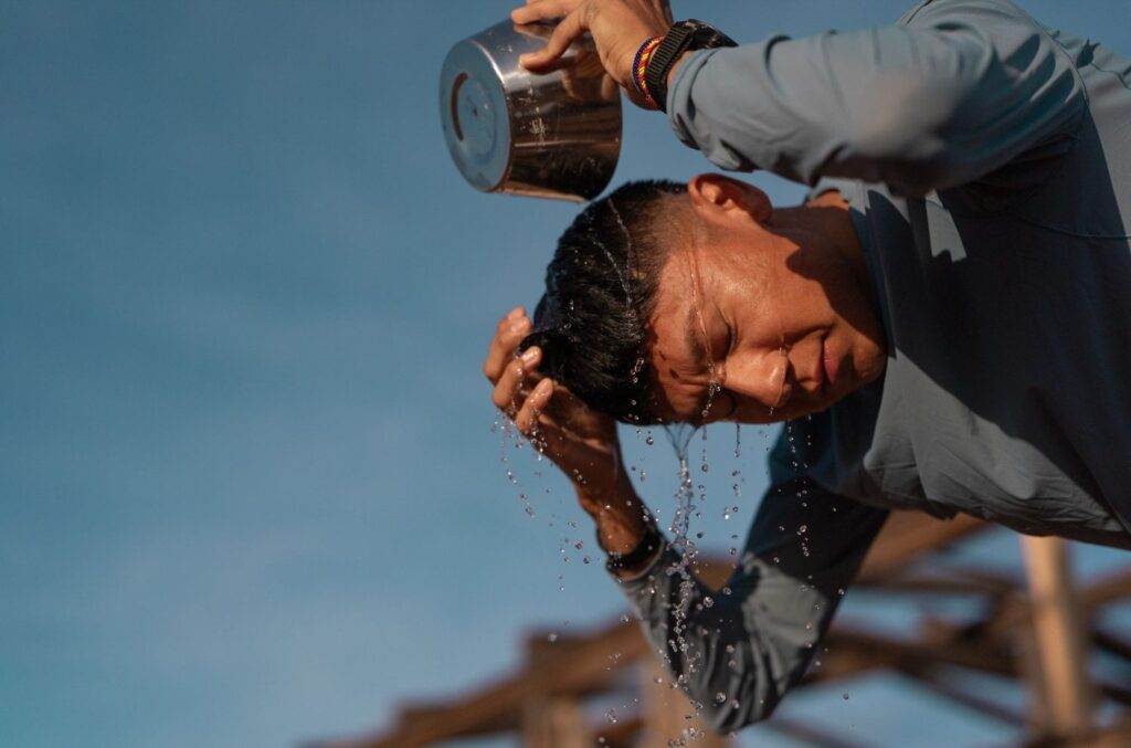 A photo of a man pouring water over his head