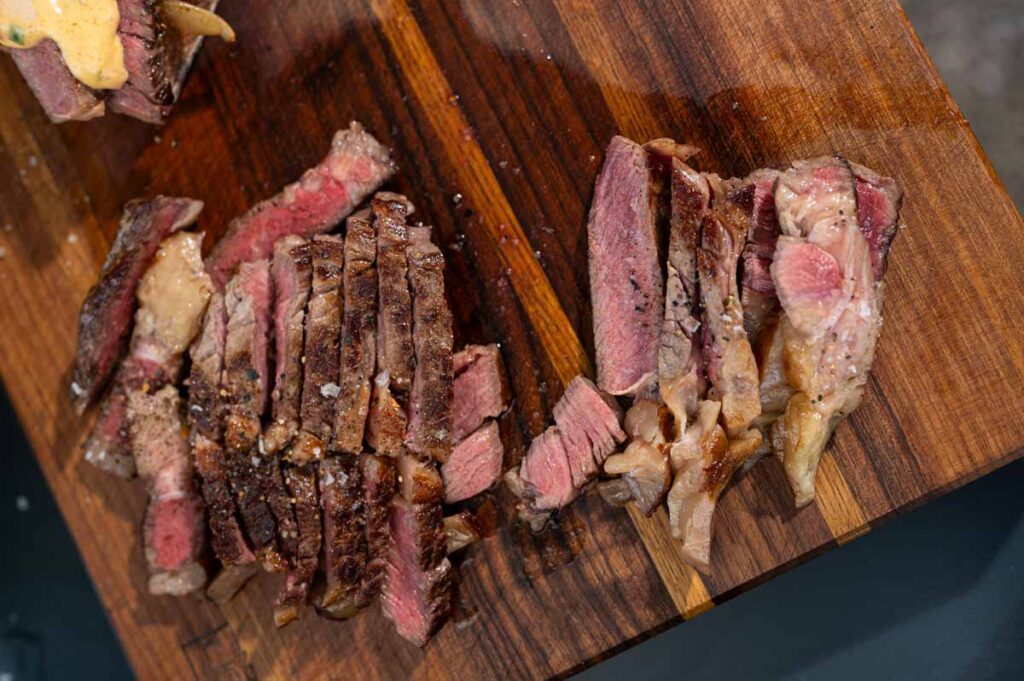 Saftige Ribeye-Steakstreifen nach dem Grillen auf der Plancha, medium rare geschnitten