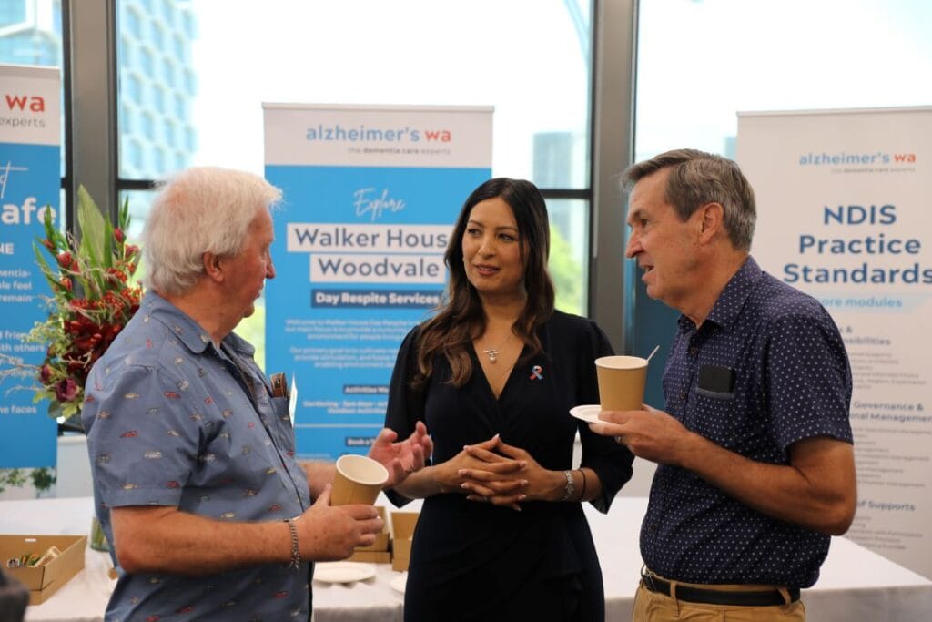 A woman and two men talking while holding coffees