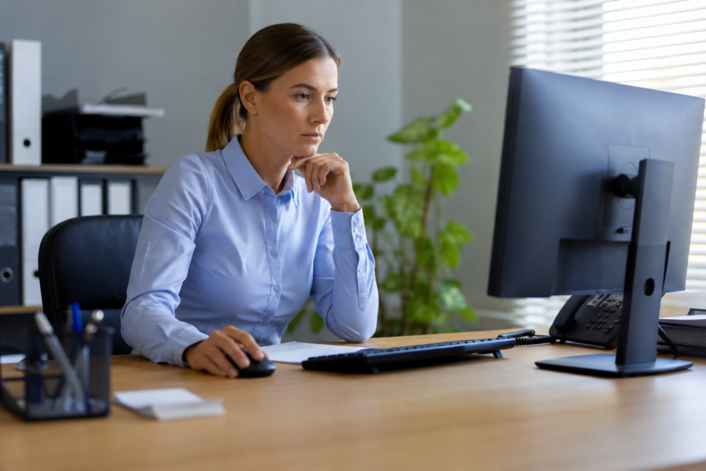 Eine Mitarbeiterin arbeitet konzentriert an ihrem Computer im Büro. Das Motiv veranschaulicht das Thema Urlaubsvertretung Sicherheitsrisiko im Arbeitsalltag.
