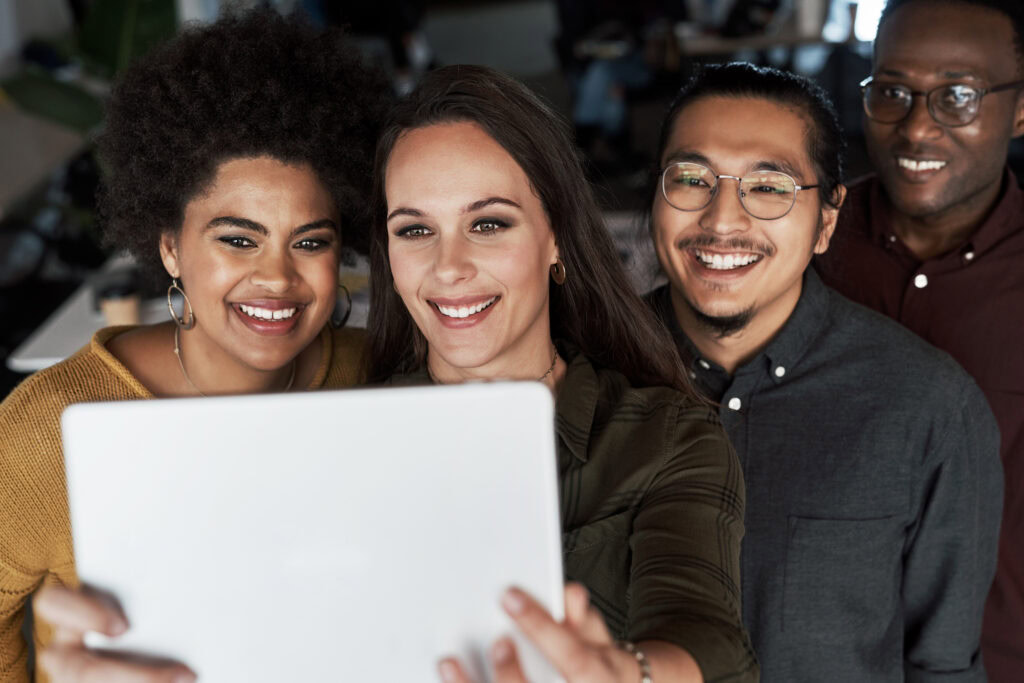 Shot of a group of young businesspeople taking selfies together with a digital tablet at work.