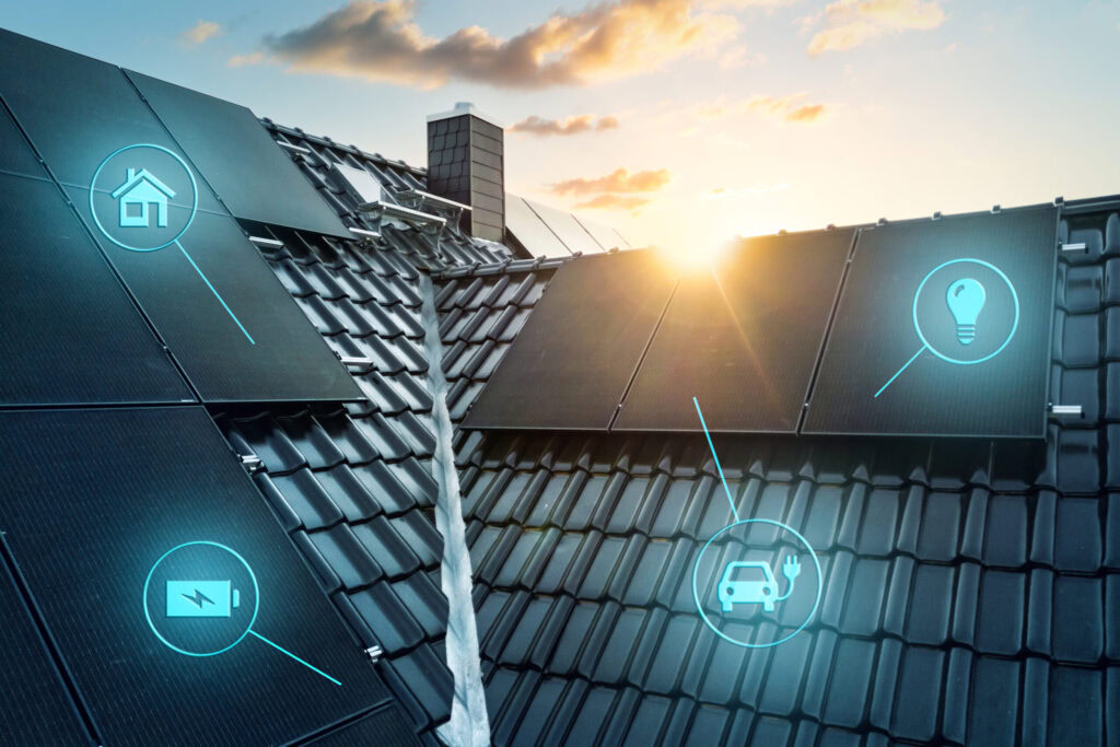 Ein modernes Smart-Home-Dach mit dunklen Solarzellen bei Sonnenuntergang, mit Symbolen für ein Smart Home, Batteriespeicher, Ladestation für Elektrofahrzeuge und Stromverbrauch im Haushalt.
