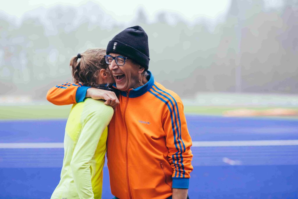 A photo of two people hugging at a running track