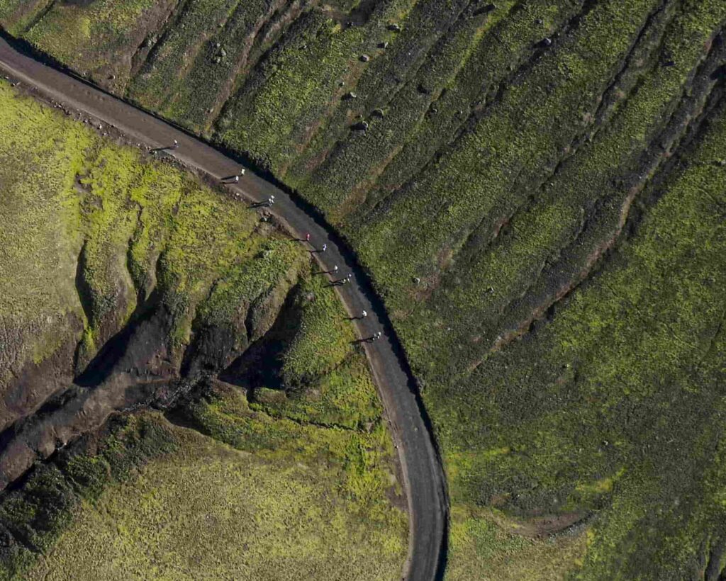A photo taken from arial view of a road running through some green hills.