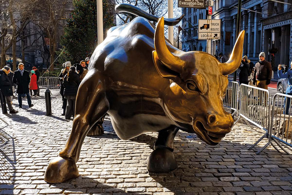 Bronzestatue des Charging Bull an der Wall Street mit Touristen im Hintergrund.