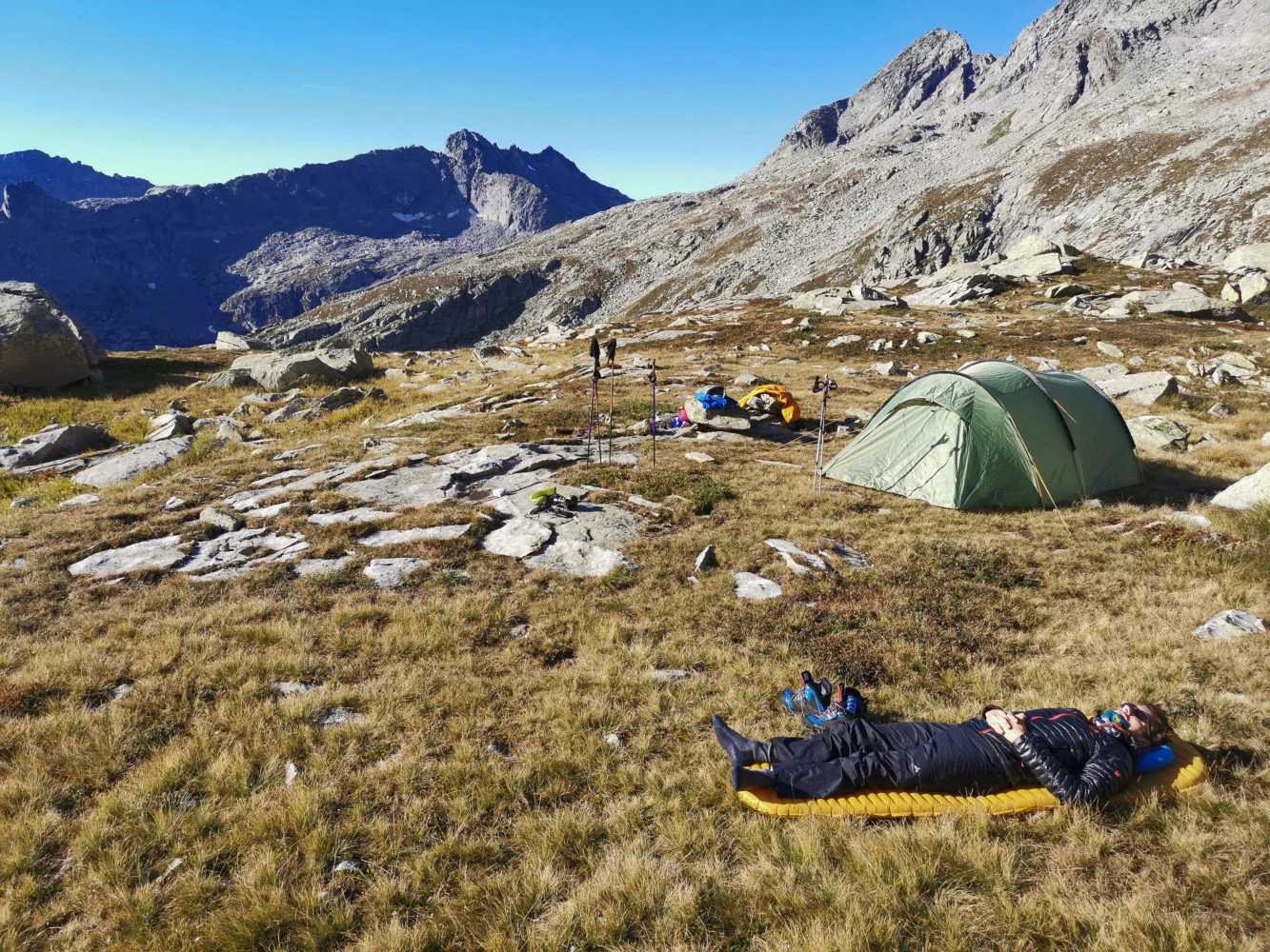 Wanderer liegt auf seiner Isomatte neben seinem Zelt in der Sonne