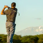 Golfer teeing off at Kilimanjaro Golf Course with Mount Kilimanjaro in the background during a luxury Tanzania safari