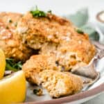Salmon cakes on a plate with a bite on a fork.