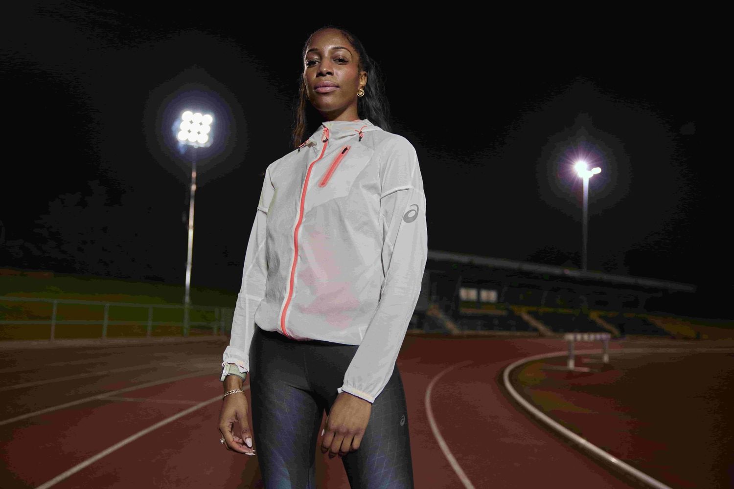 A photograph of a woman standing on a running track