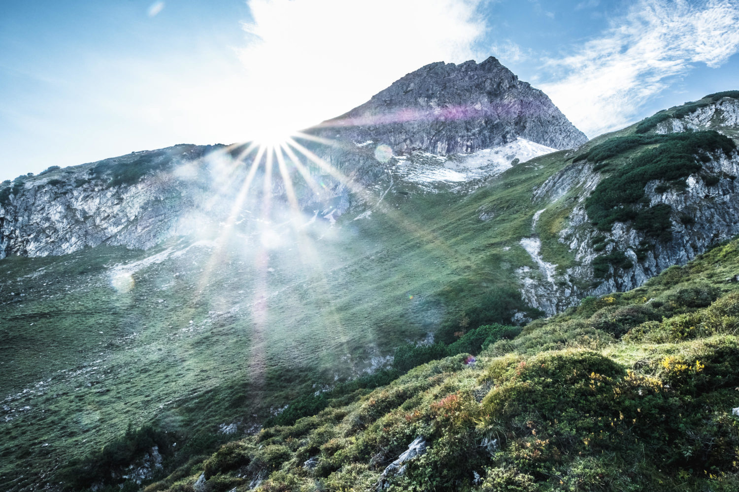 Sunstar am Berghang mit grünen WIesen