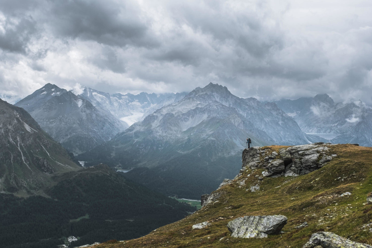 Wanderer steht an Felsvorsprung mit Blick auf die Berge