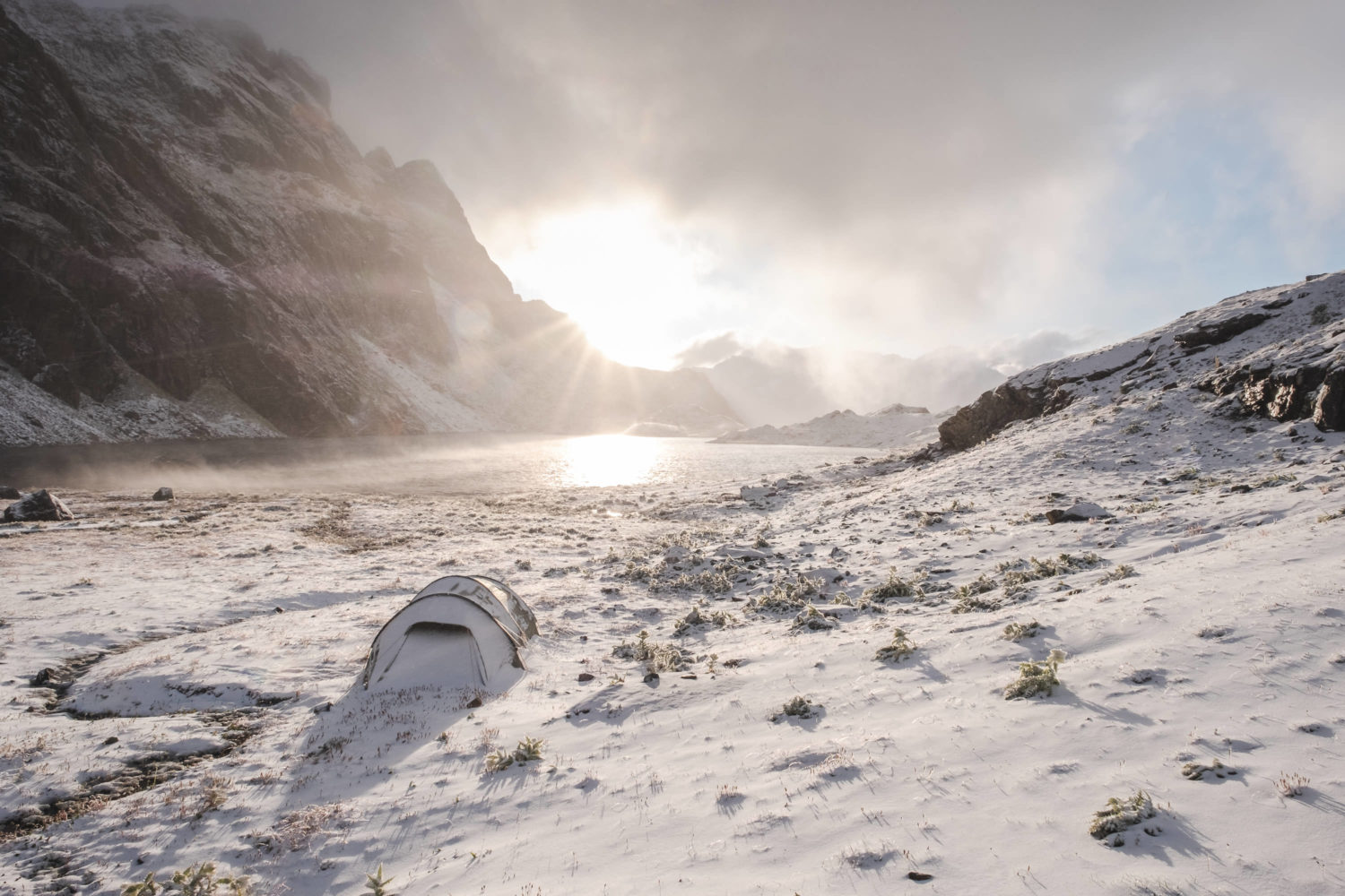 Eingeschneites Zelt mit Lunghinsee im Hintergrund beim Sonnenauf