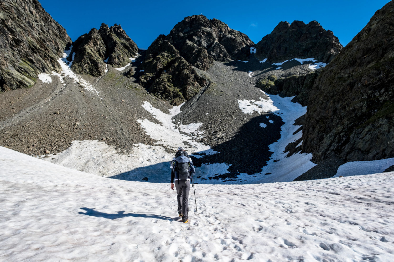 Wanderer läuft durch Schnee auf Berghänge zu