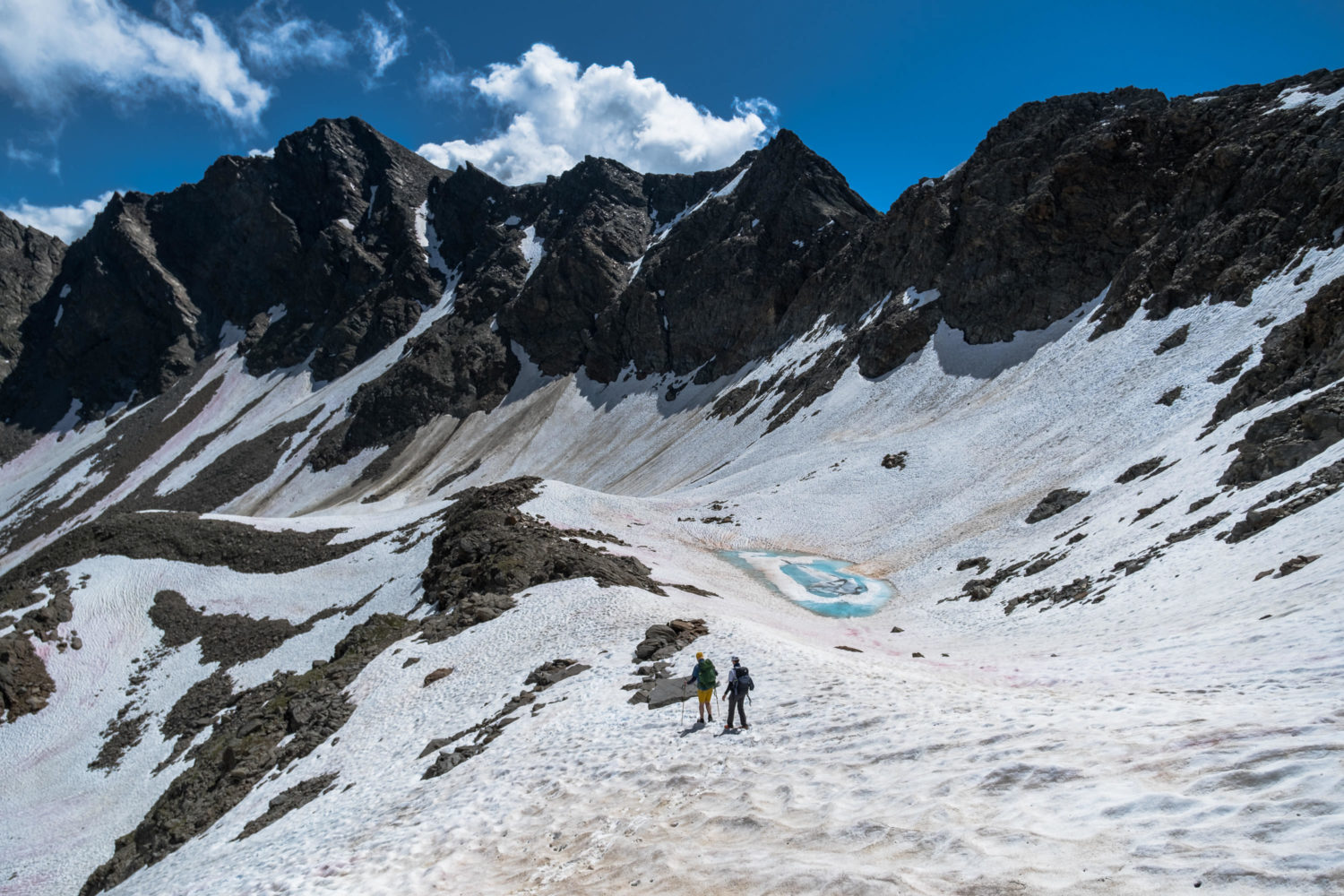Zwei Wanderer laufen durch den Schnee in einem Bergkessel