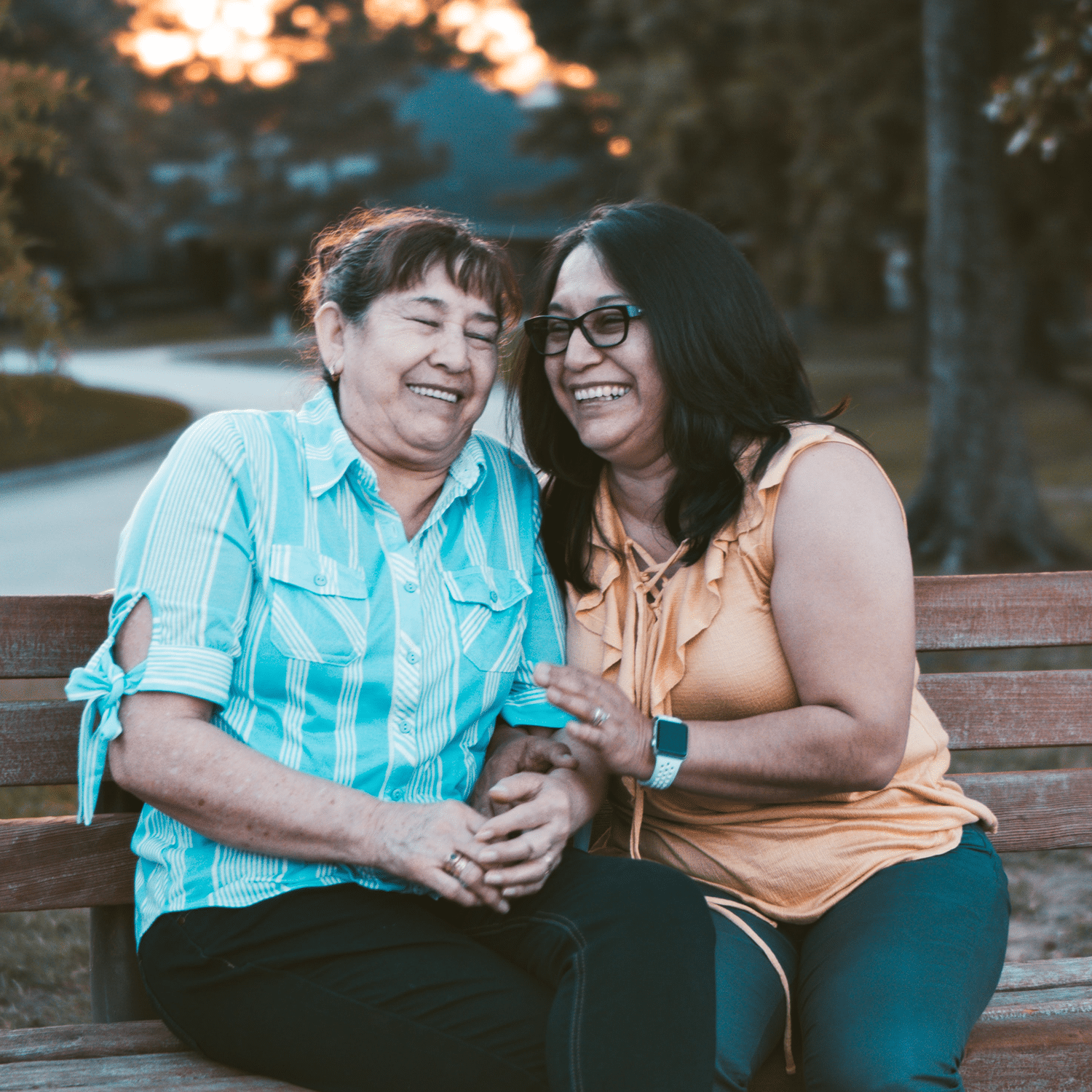 two women laughing on park bench