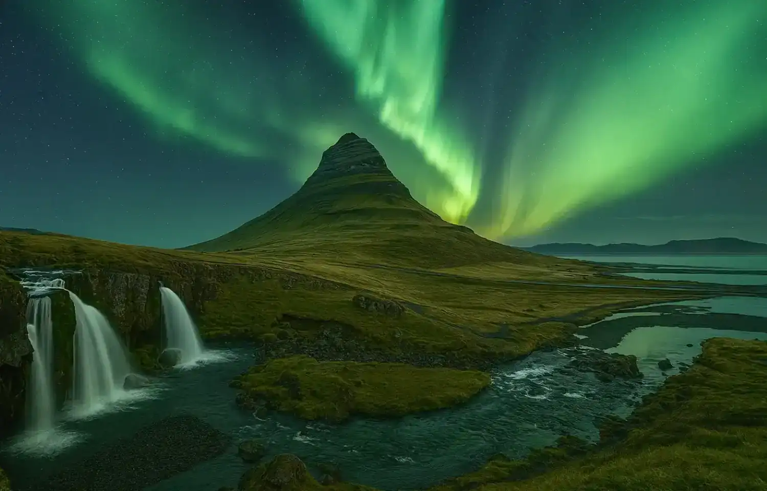 Northern Lights over Kirkjufell mountain with waterfalls and river in Iceland.