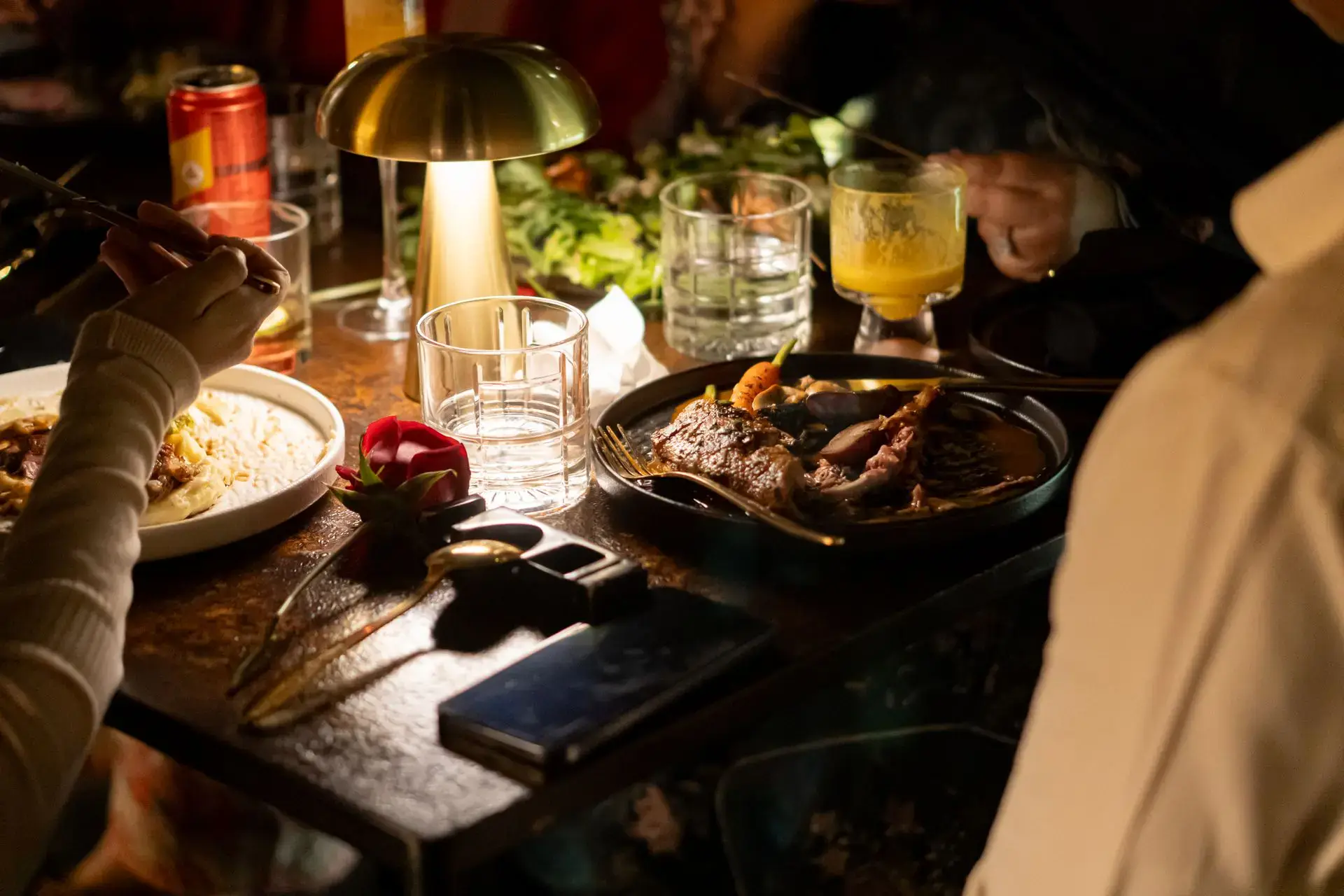 Diners sharing plates by candlelight at a warmly lit restaurant table