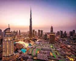 منظر علوي لبرج خليفة ومنطقة داون تاون دبي مع إطلالة على دبي مول والنافورات وقت الغروب.