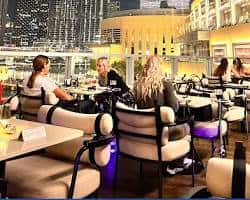 جلسات شيشة خارجية في دبي مول ليلاً مع إضاءة النافورة