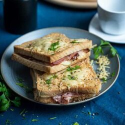 Frisch gebratenes Croque Monsieur Sandwich mit geschmolzenem Käse, goldbraunem Toast und Schinken auf einem Teller serviert