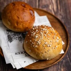 Frisch gebackene Potato Rolls aus Kartoffelteig – fluffige, goldbraune Burger Buns auf einem Holzbrett, ideal für selbstgemachte Burger