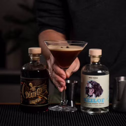 Fertiger Espresso Martini mit cremiger Schaumkrone und drei Kaffeebohnen als Garnitur im Martiniglas.