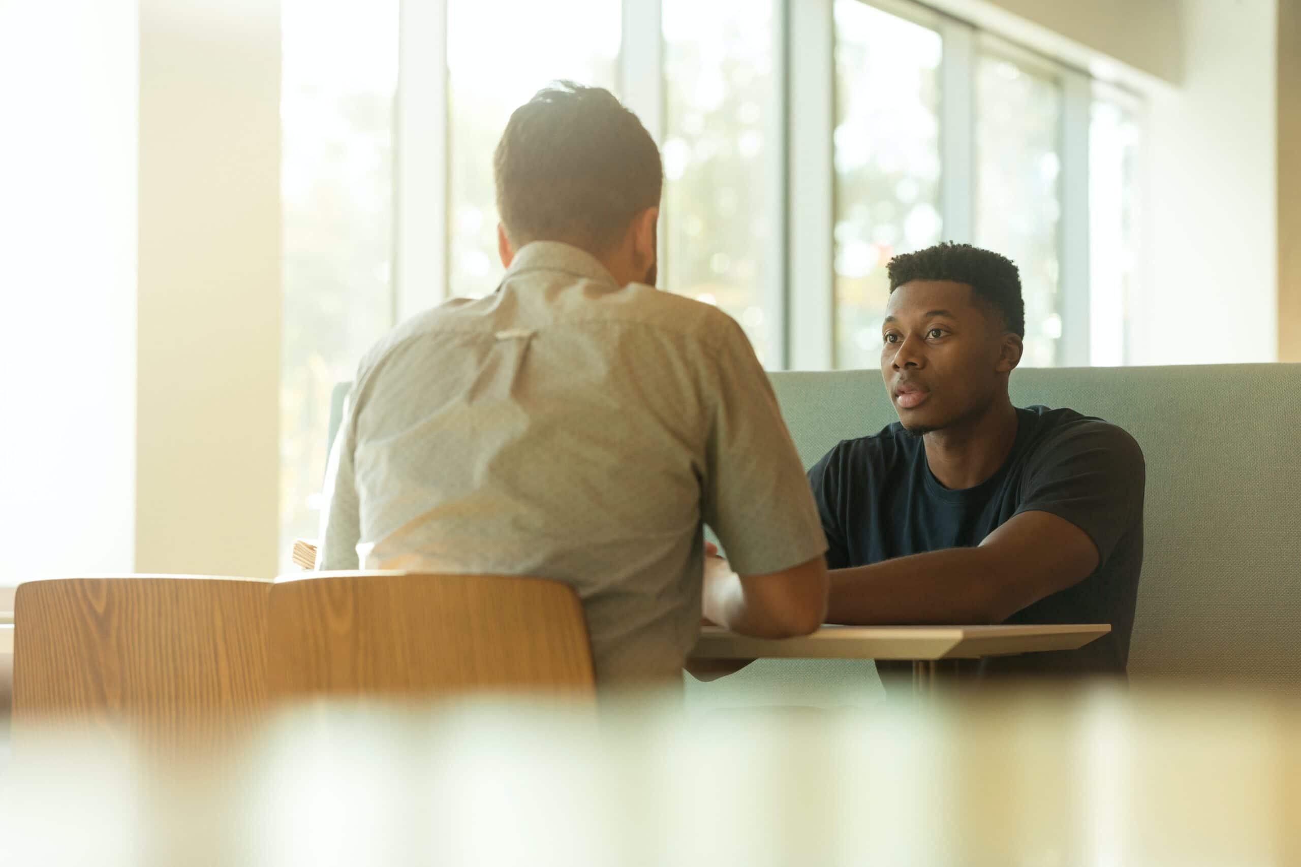 two males chatting at a table