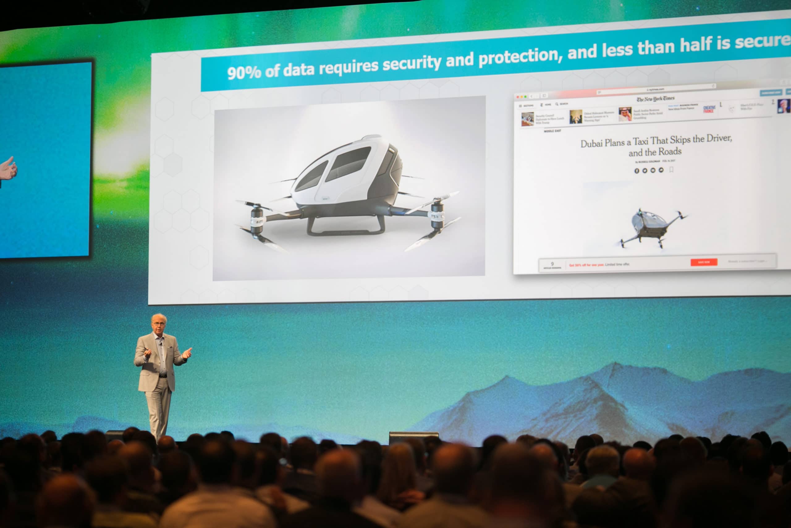 Speaker on stage presenting a slide of a futuristic pod-like vehicle; audience visible in the foreground.