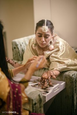 Muslim bride's hands with intricate mehndi designs during a vibrant ceremony
