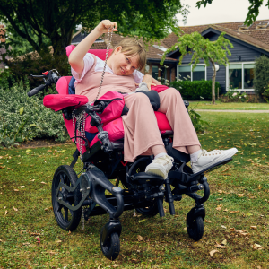 Close-up lifestyle image of Sophie using a wheelchair fitted with a pommel for lower limb positioning