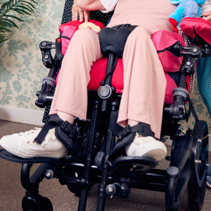 Close-up lifestyle image of Sophie using a wheelchair fitted with a pommel for lower limb positioning