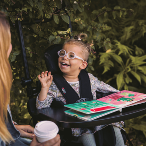 Close-up of Doris in her wheelchair with activity tray, laughing while looking at her mum