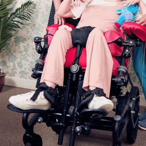 Close-up lifestyle image of ankle huggers securing a user’s ankles on a wheelchair footplate
