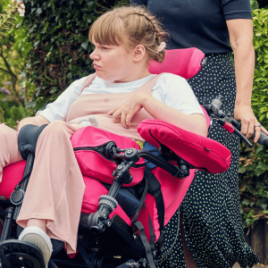 Lifestyle image of Sophie using a wheelchair fitted with height adjustable multiplane arm supports (pair)