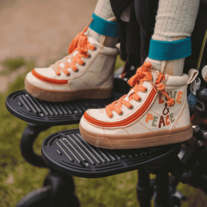 Close-up of Doris’s feet wearing colourful ankle boots resting on wheelchair footplates