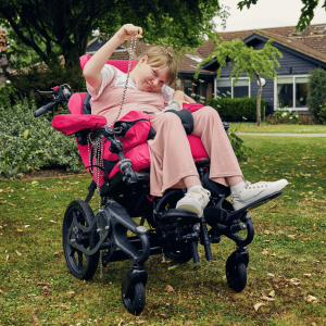 Close-up lifestyle image of Sophie using a wheelchair fitted with a pommel for lower limb positioning