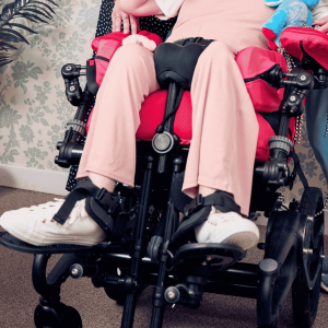 Close-up lifestyle image of Sophie using a wheelchair fitted with a pommel for lower limb positioning