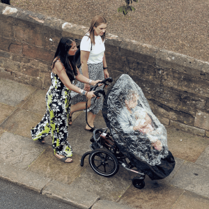 Lilac in her wheelchair with raincover on being pushed by her mum across a bridge in Hereford