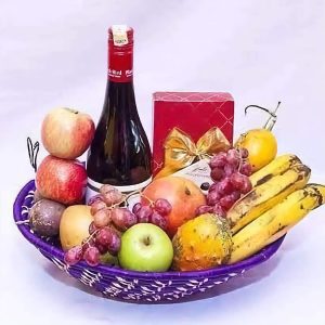 Fruit Basket Combo with red wine, Belgian chocolate, bananas, grapes, apples, melons, and tomatoes – luxurious gift basket by Nectar Flower Shop Nairobi.
