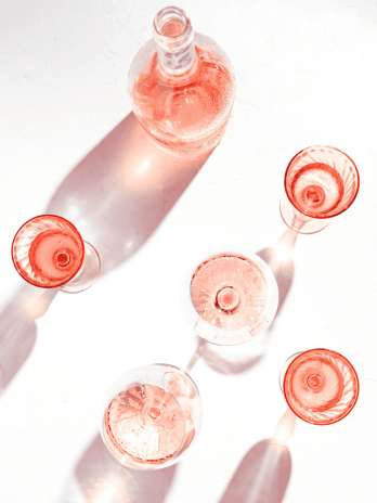 Elegant pink champagne glasses with a bottle on a white background.