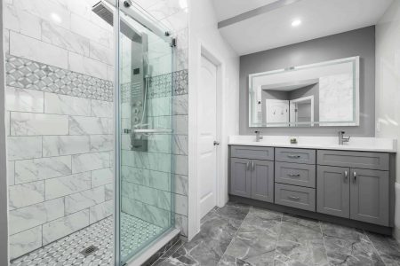 Luxurious modern bathroom featuring grey cabinets and a marble-tiled shower.