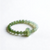 A delicate green jade bead bracelet with a larger, oval jade bead charm, displayed on a clean white background.