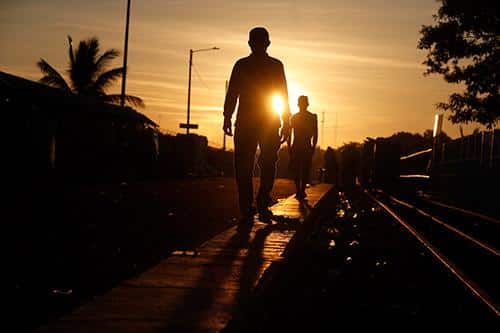 Dos hombres caminando por la calle al atardecer a contraluz