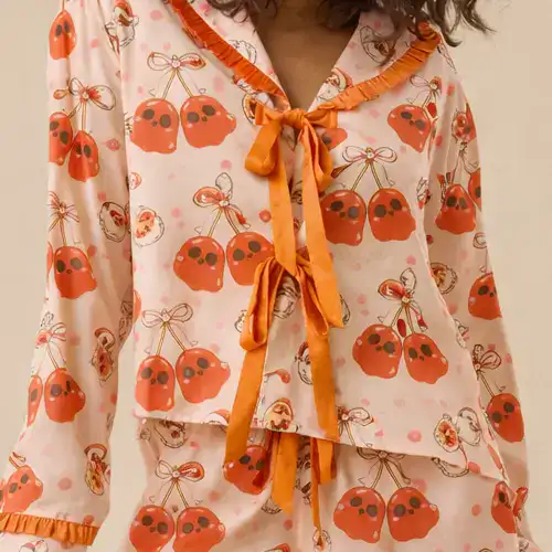Y2K inspired sweet pink pajama shorts set featuring a mix of cherry motifs and subtle Halloween skull and pumpkin graphics, ruffle trim details, soft and breathable fabric.