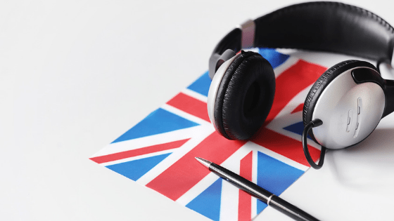 su uno sfondo bianco ci sono una bandiera inglese, una penna e un paio di cuffie