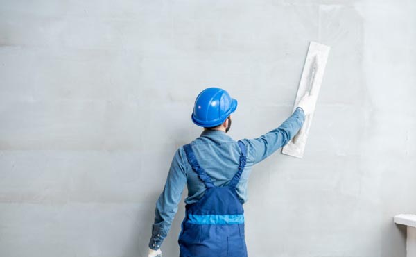 Worker applying Ideal Drymix wall plaster for smooth interior finish