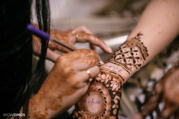 Muslim bride's hands with intricate mehndi designs during a vibrant ceremony