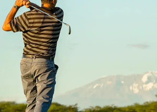 Golfer teeing off at Kilimanjaro Golf Course with Mount Kilimanjaro in the background during a luxury Tanzania safari