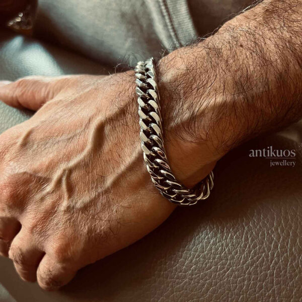 Man wearing silver chain bracelet on wrist.